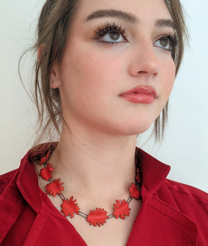 abstract red shapes necklace on model with red shirt